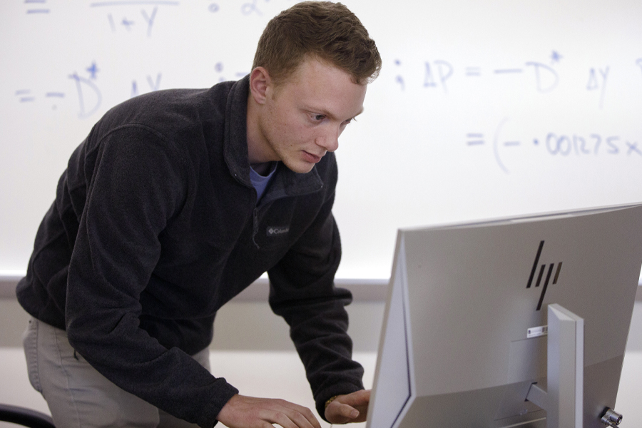 Dylan Riley bends down to look at a computer.