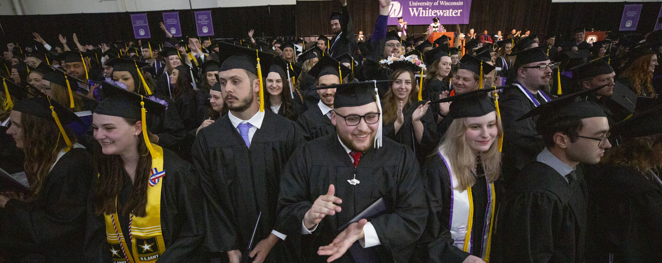 Graduates in their caps and gowns clap during the ceremony.