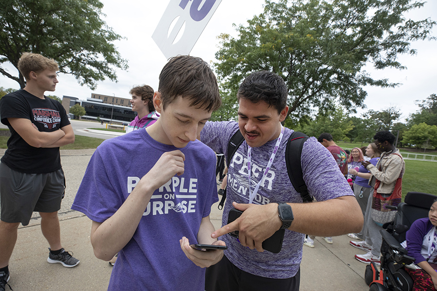 Two students wearing purple shirts stand together during HawkFest.