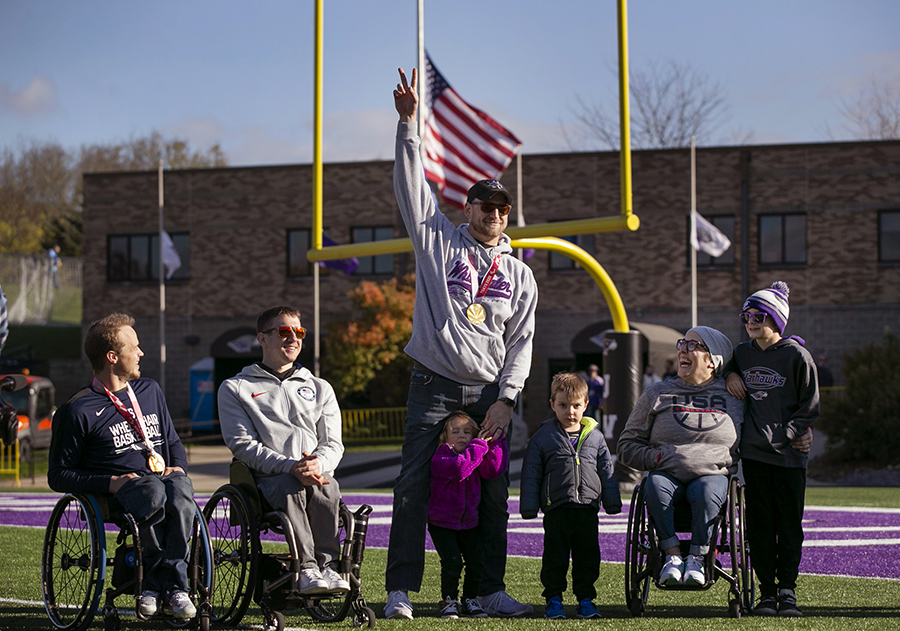 Paralympians and Warhawk alumni stand on the UW-Whitewater football field.