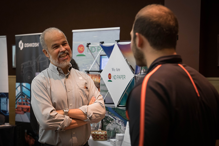 A faculty member smiles and chats with a student.