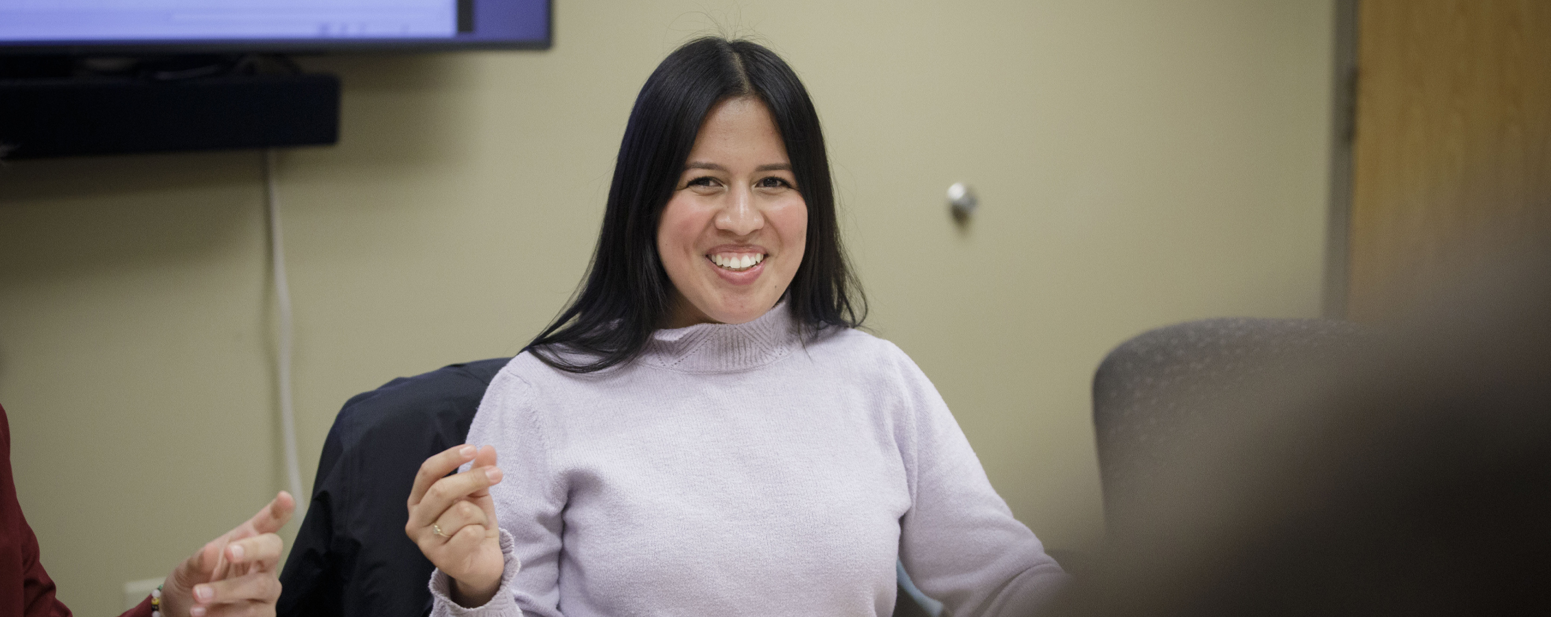 Maria Pacheco sits at a table with a smile on her face.