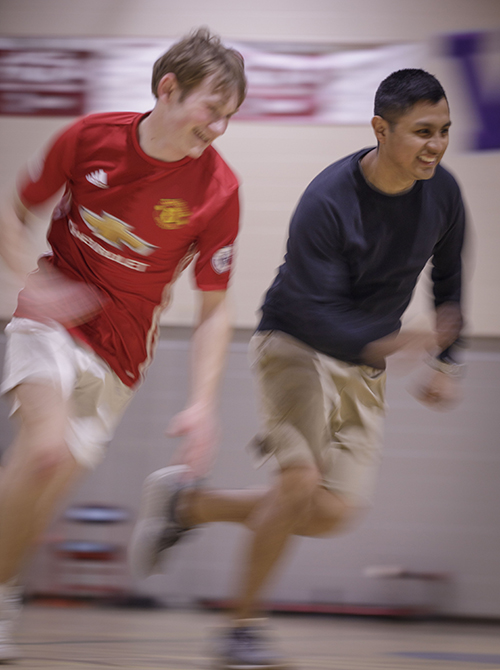 Two students run together with smiles on their faces.