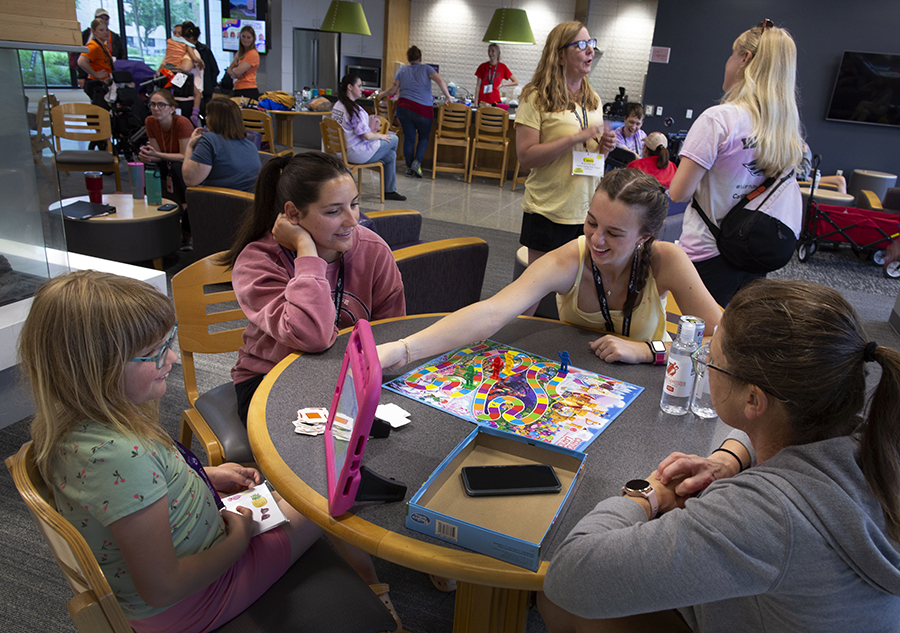 Four people, including a child, sit a table to play a board game. 