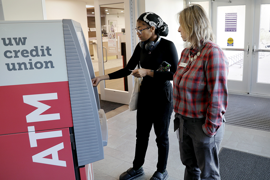 Two people use an atm on campus.