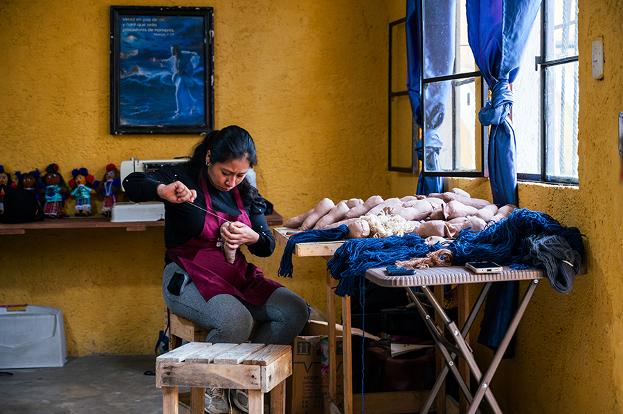 A Guatemalan woman works in a shop making dolls. 