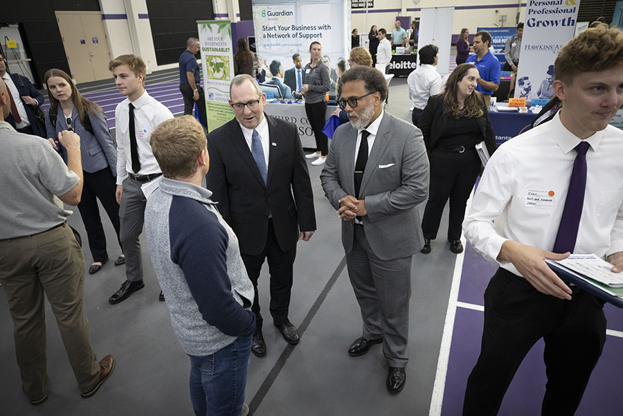 The White House National Cyber Director speaks with people at the career fair. 