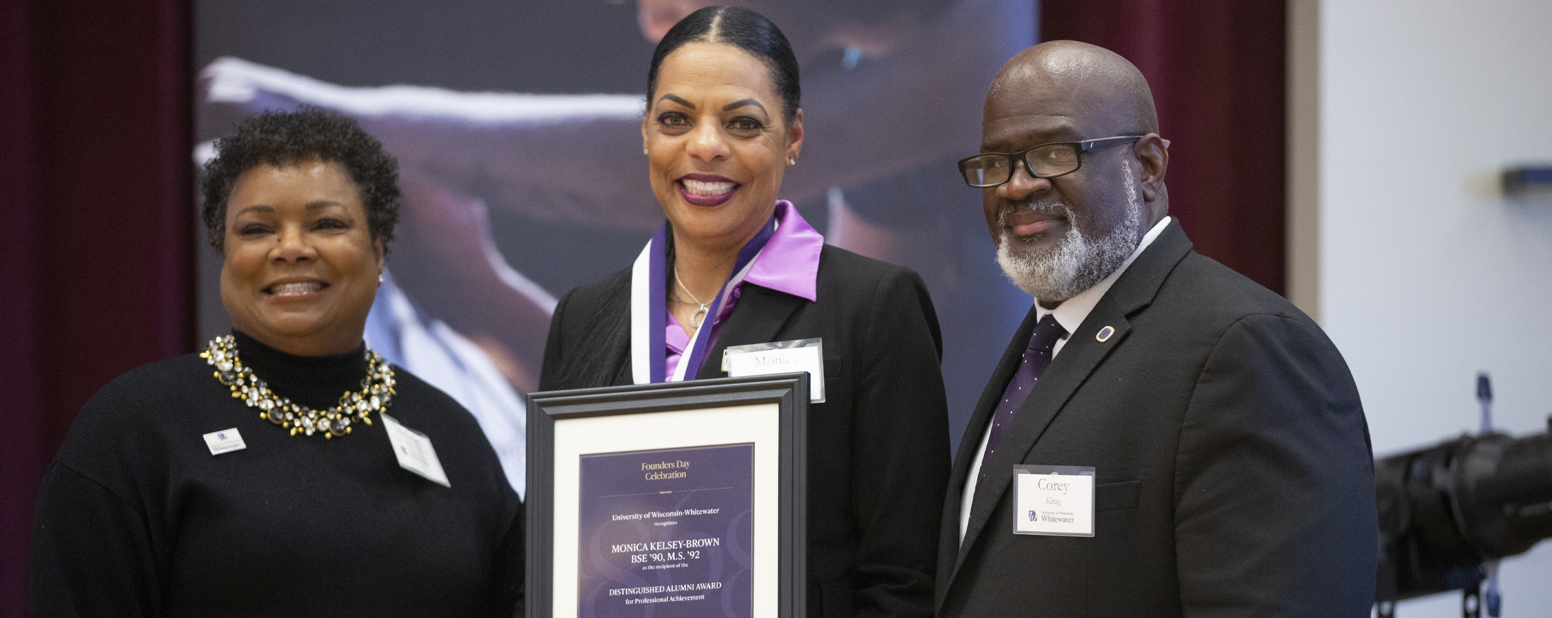 Monica Kelsey-Brown stands with Michelle Buckingham and Chancellor King while she holds a plaque.