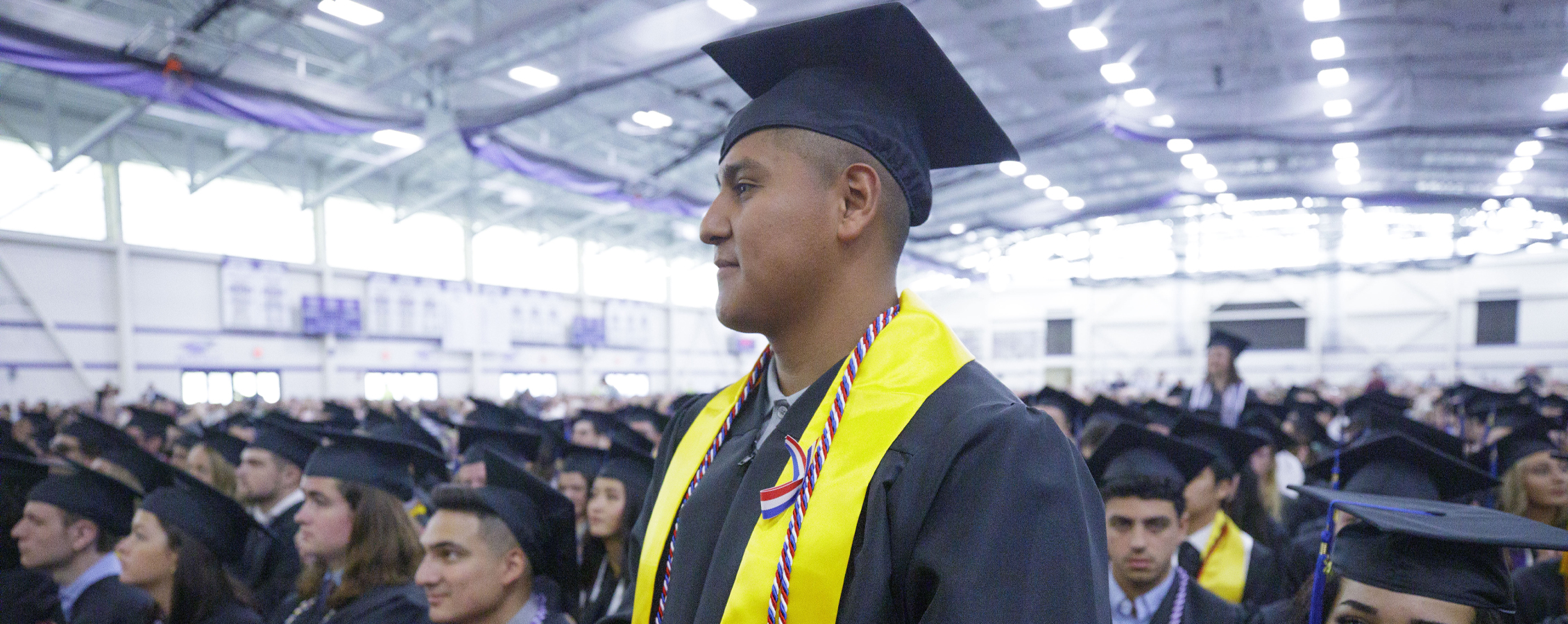 A military student stands during commencement as they are recognized.