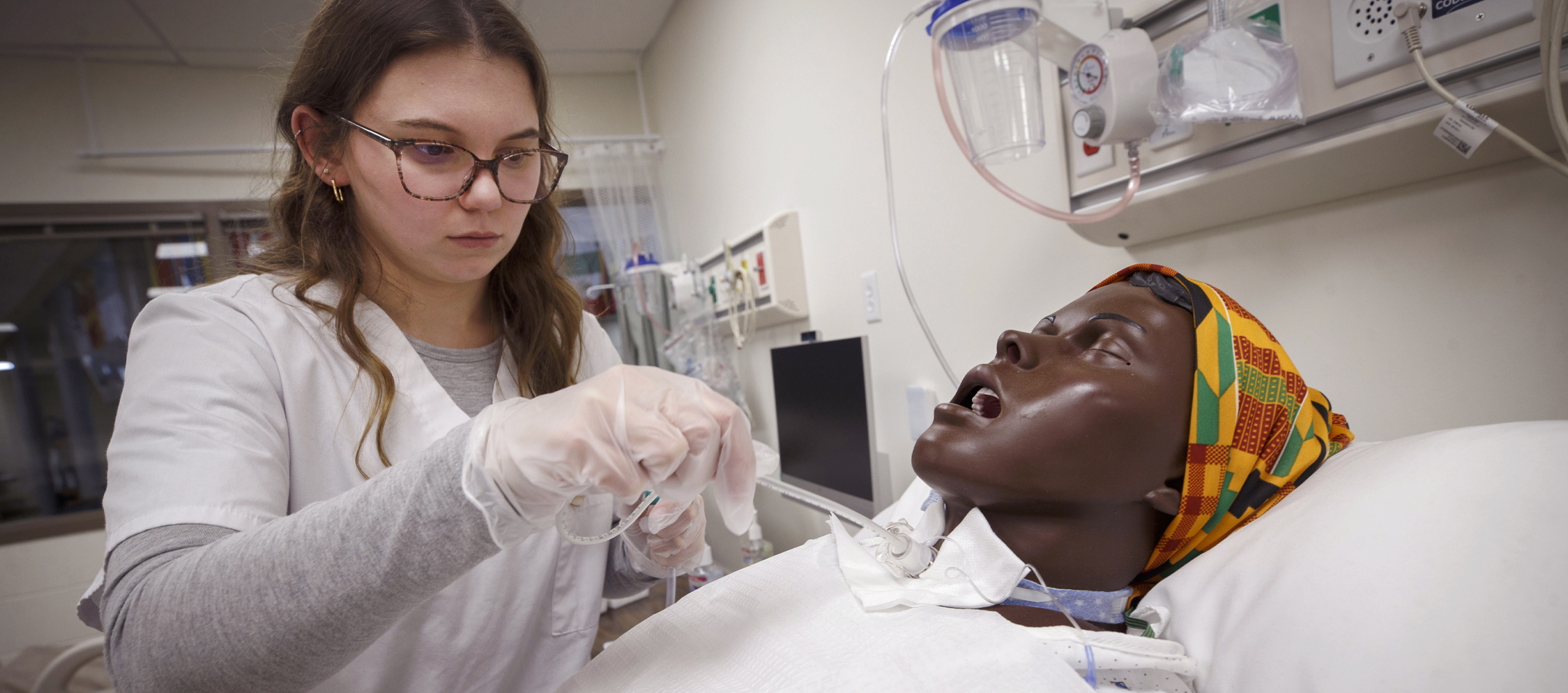 A student performs a simulated tracheotomy on a medical training manikin.