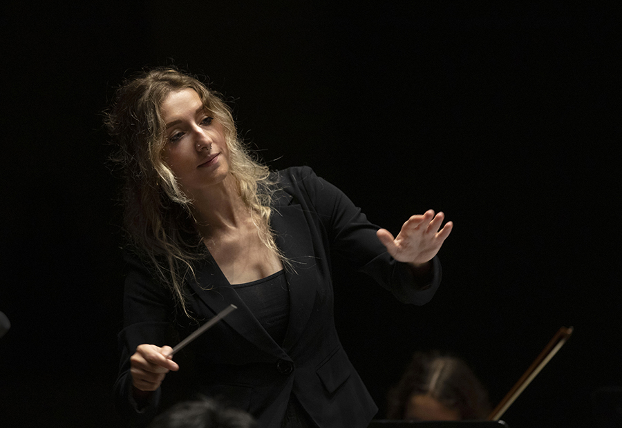 A student wearing a black shirt holds up a conducting baton.