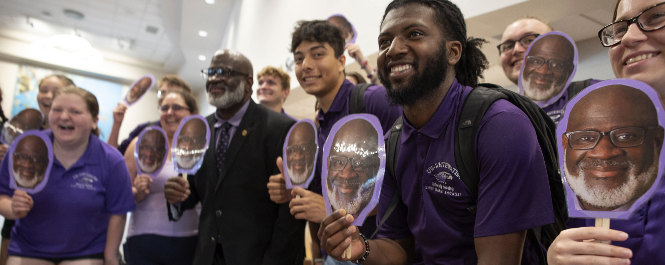 Chancellor King stands with a large group of students who are holding a paper cut out of his head.