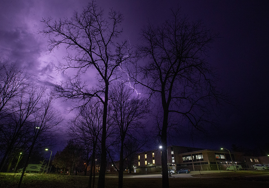 A bolt of lighting crosses the sky behind Hyer Hall and the sky looks purple.