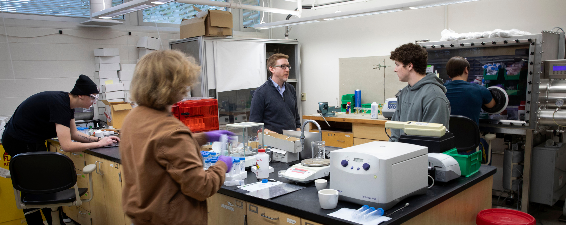 Three people work together in a classroom lab.