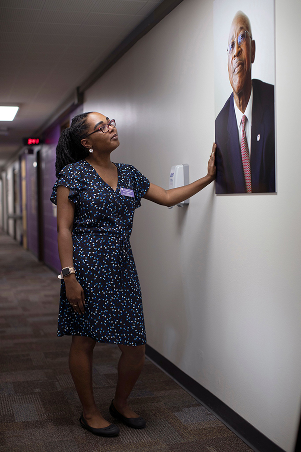 Terri Jones stands in a hallway and looks at a portrait of Dr. Pulliam hanging on the wall.