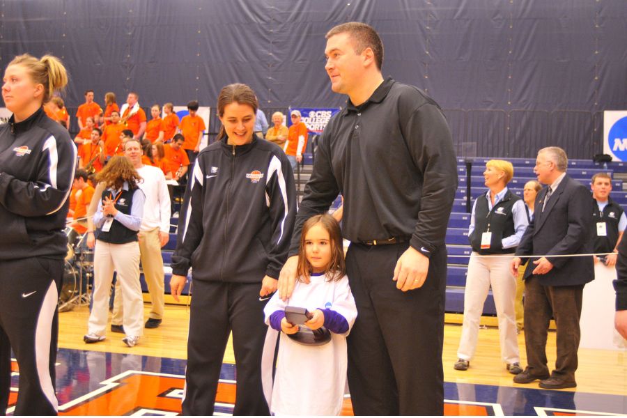 A young Kacie Carollo holds an individual trophy between her parents, Keri and Joe Carollo.