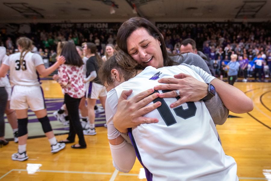 Keri Carollo hugs her daughter Kacie, guard on the Warhawks, while players react after defeating UW-Oshkosh.