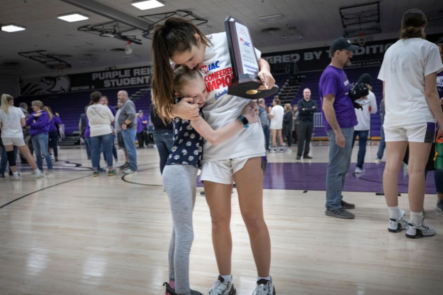 Kacie Carollo hugs a little girl as she holds a trophy.