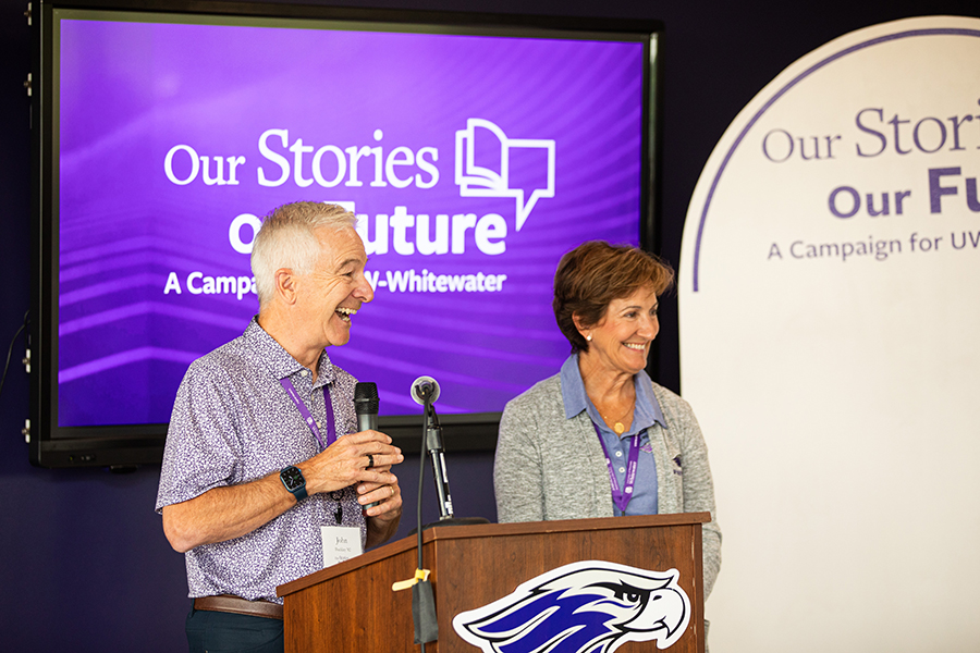 Two people stand at a podium with smiles on their faces.