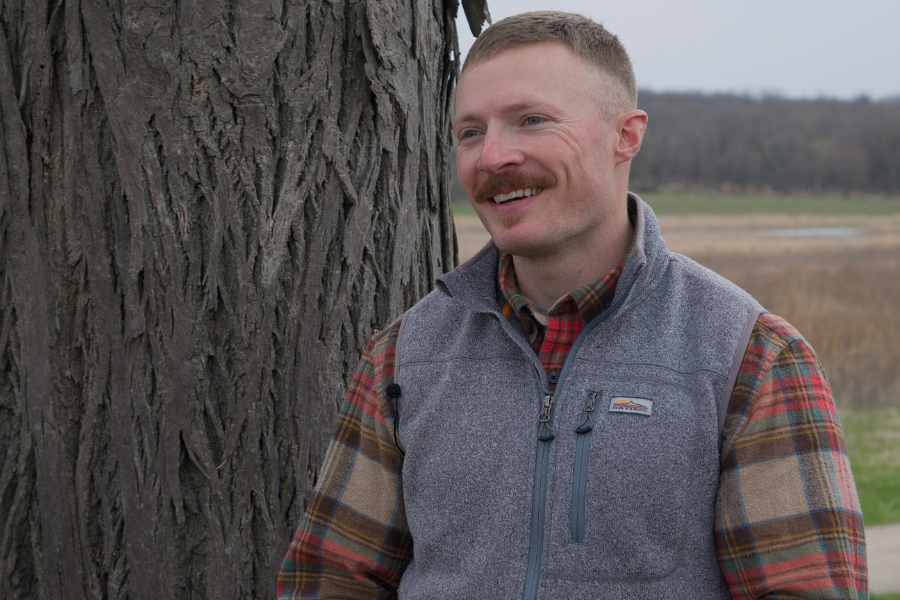 Tyler stands by tree.