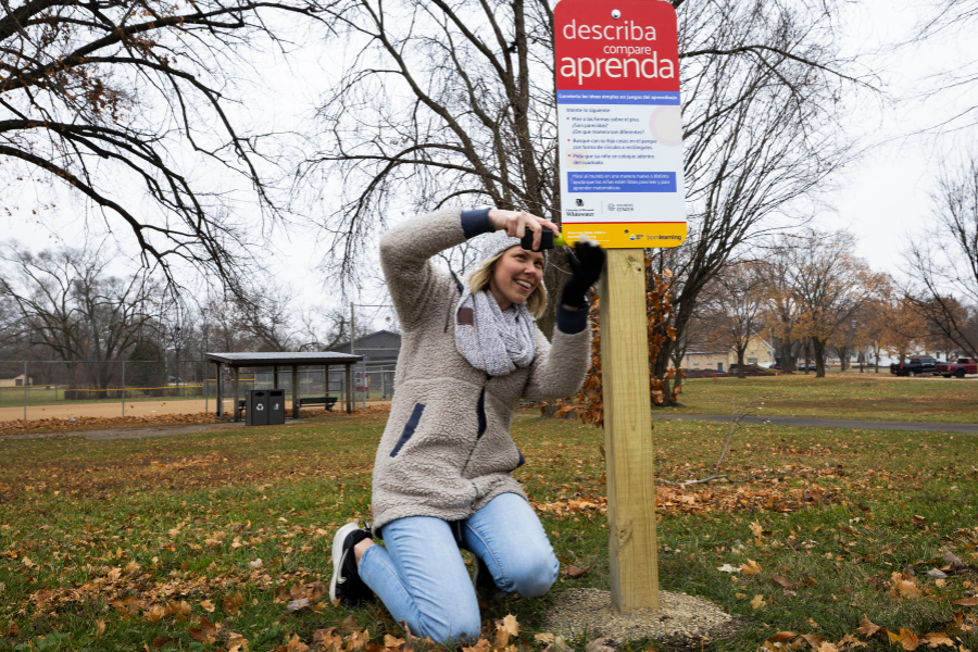 Jennalee Johnson, an early childhood education teacher at the UW-Whitewater Children’s Center, helps to install a Spanish-language sign for the Born Learning Trail in Starin Park.