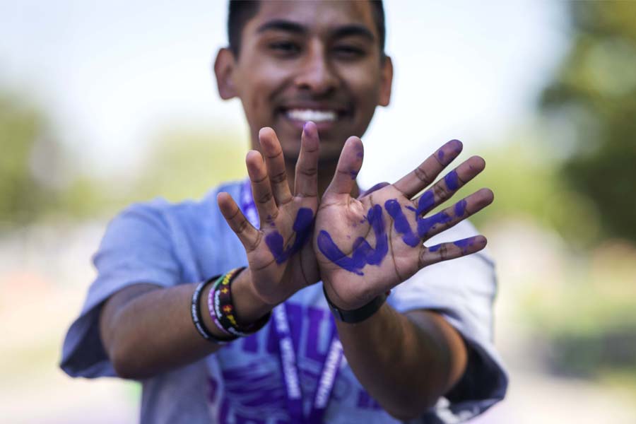 Man smiling with UWW painted on his hands in purple.