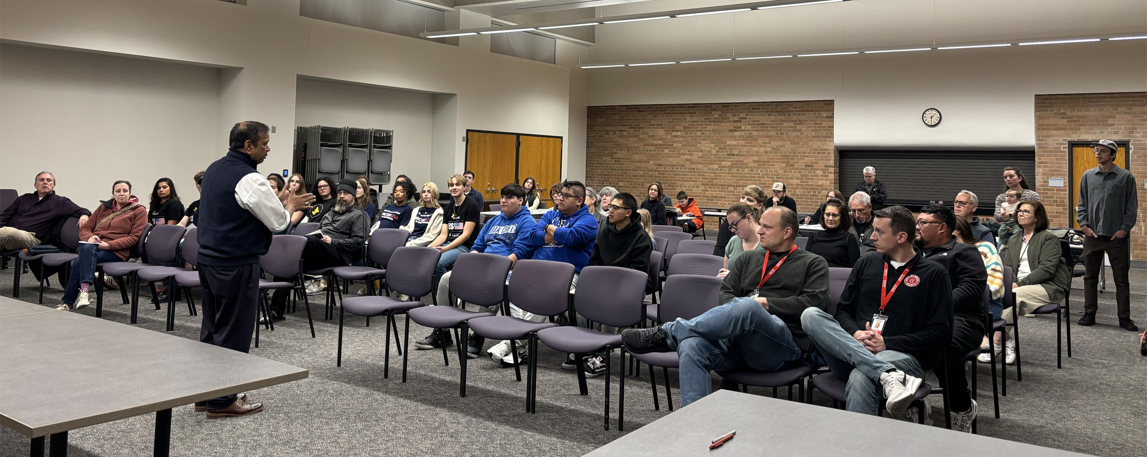 A person stands in front of several people sitting in chairs.