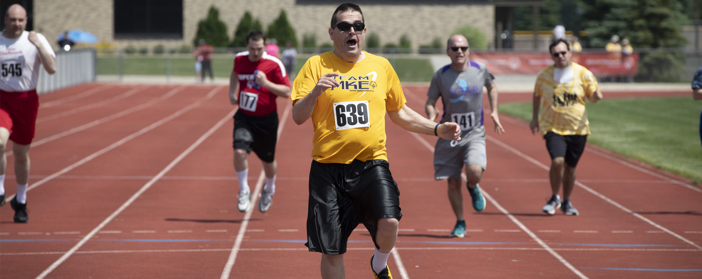 Athletes running on track during Special Olympics race.