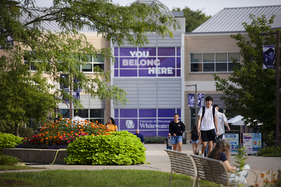 Students walk down a sidewalk in front of the University Center.