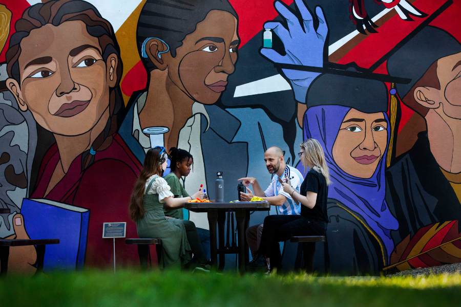 A few people are sitting in front of a large mural.