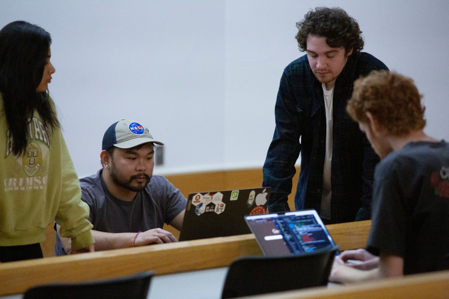 Students collaborate around a laptop.