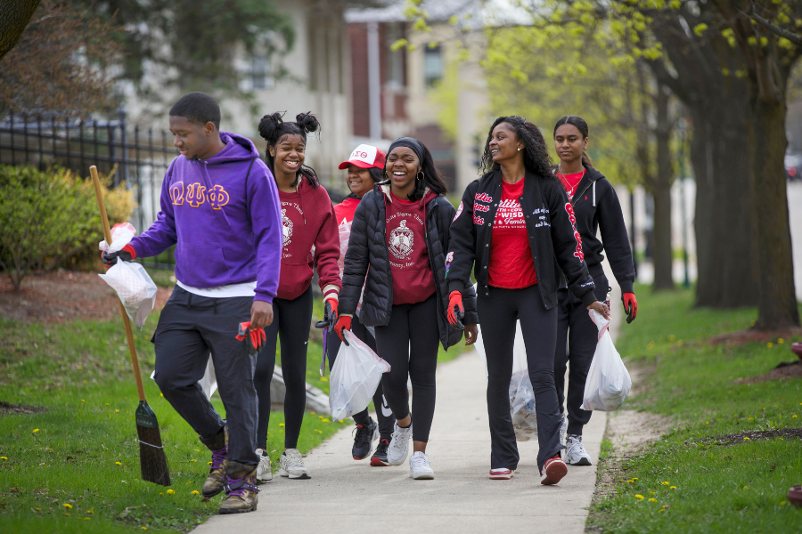 Students walk on sidewalk with trash.