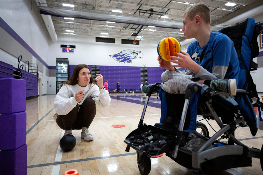A student does sign language with a younger student.