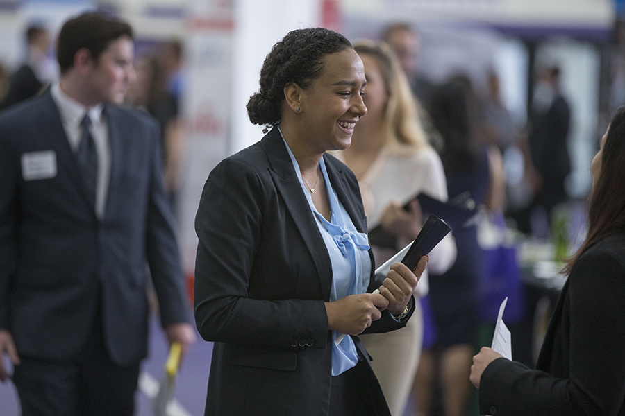 Smiling student holding binder at Hawk Career Fair