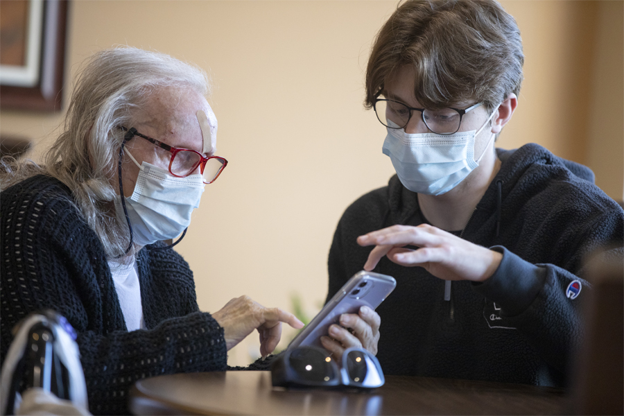 woman assisting a senior man with his phone