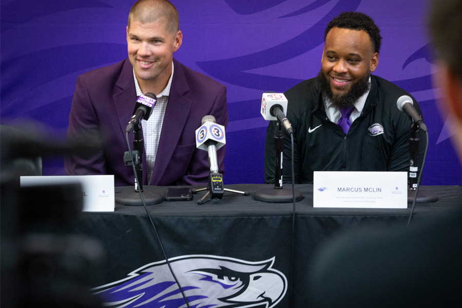 head coach Jace Rindahl sits with Associate Head Coach Marcus McLin as they are behind microphones on stage at a conference