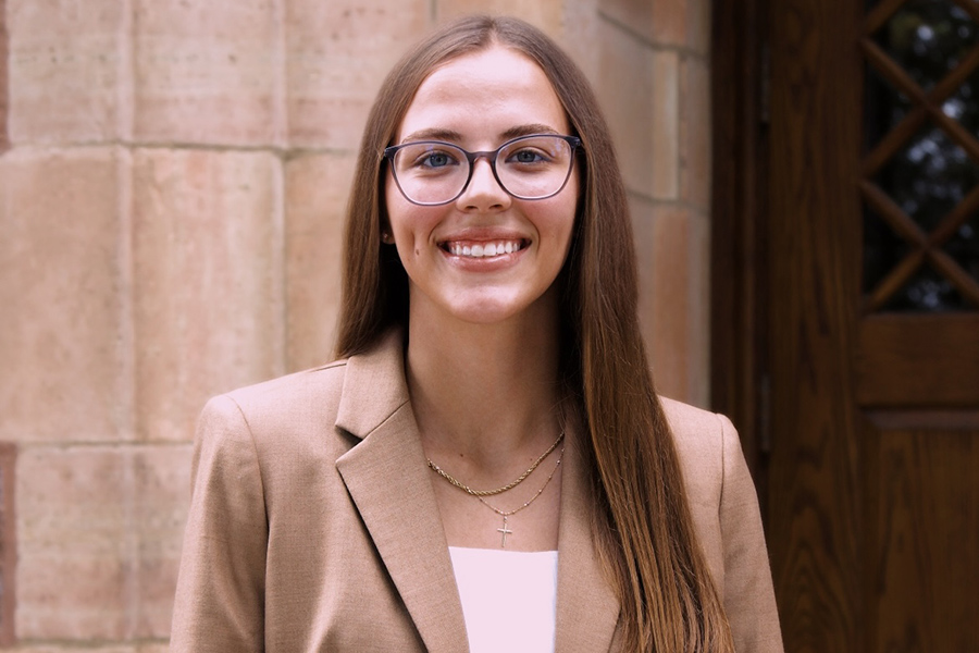 Headshot of Olivia Sheets standing in front of a brick wall with a white shirt and tan blazer