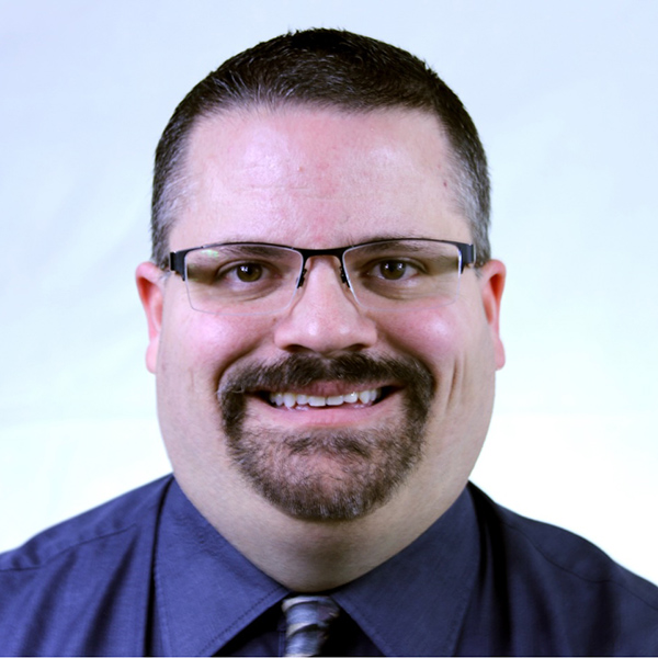 Image of Terry Tumbarello wearing a purple shirt and purple tie.