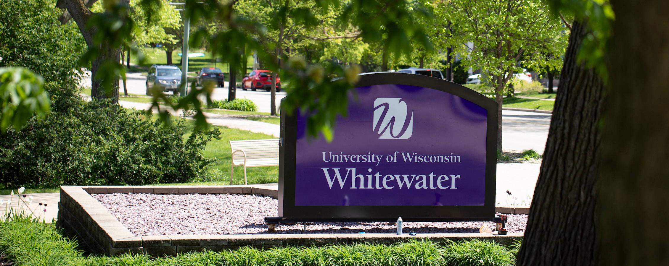 Image of the UW-Whitewater campus sign with green trees in the foreground