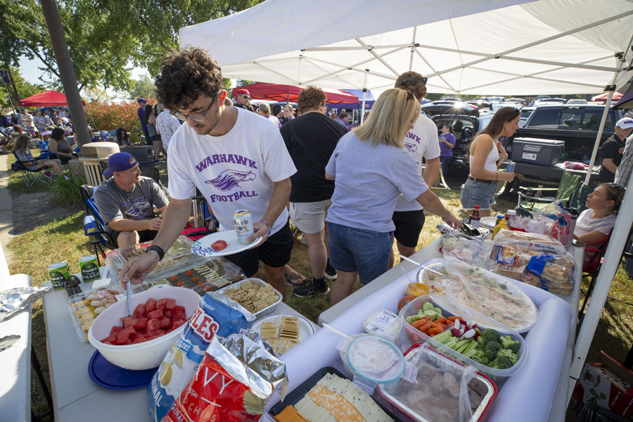 A family tailgating under a tent filled with food.