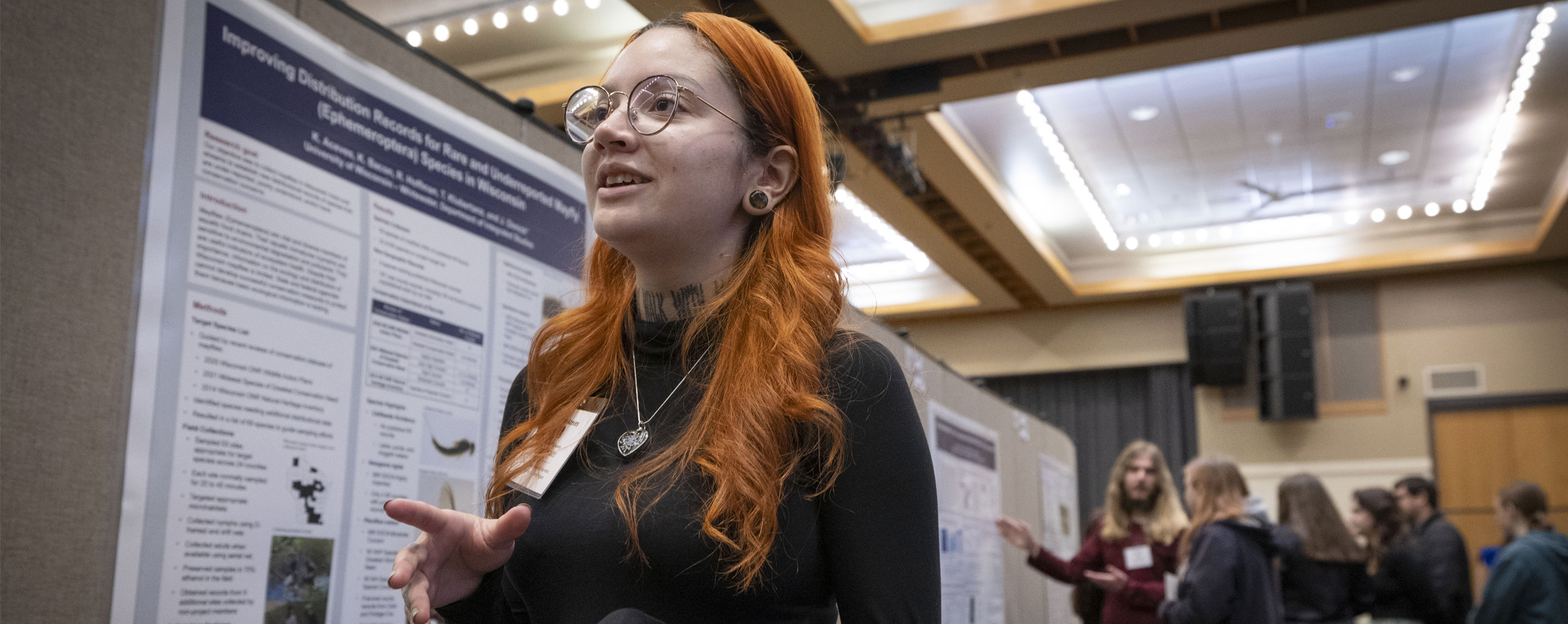 Female student talking in front of research poster.