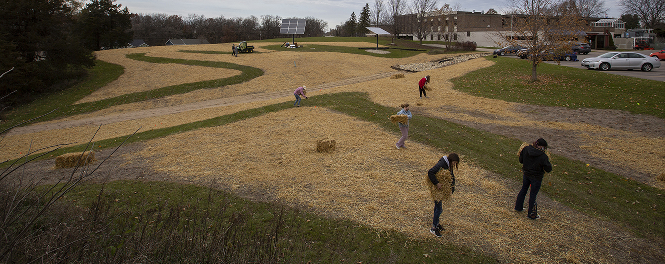 Student laying hay down in a grass field