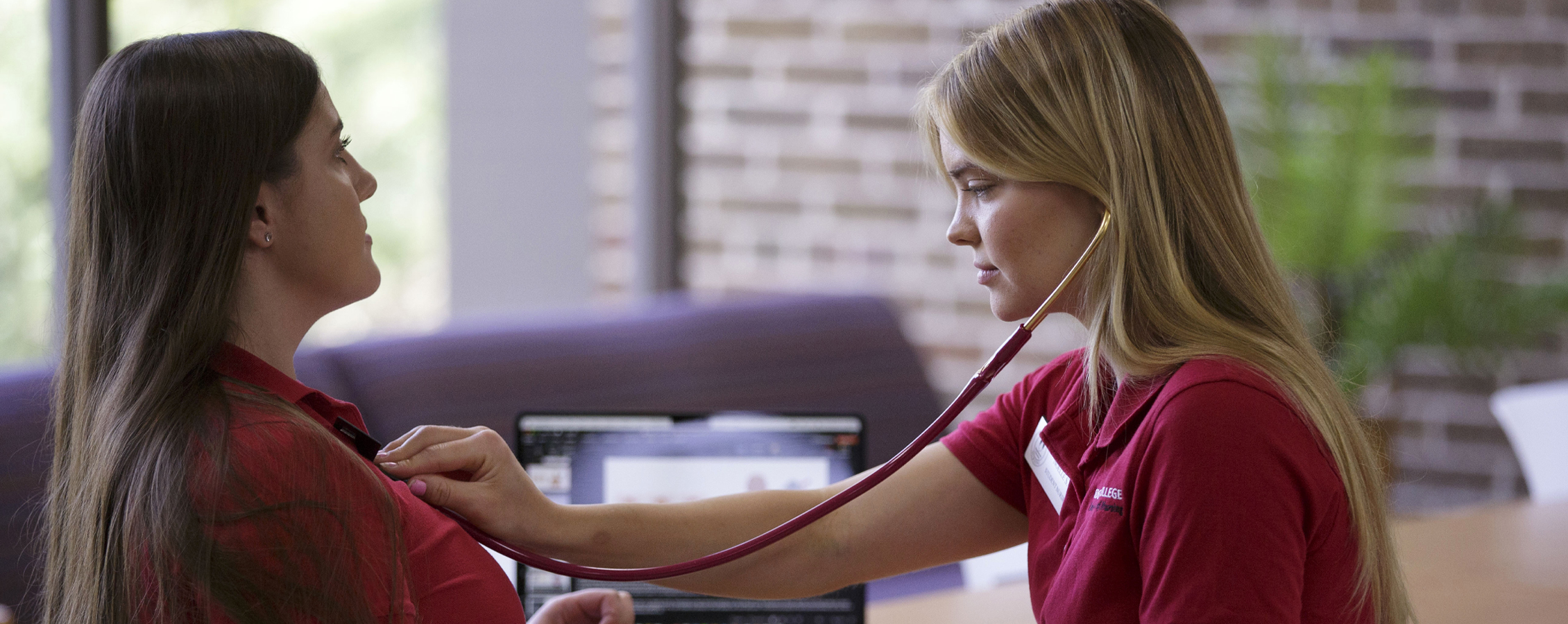 A student uses a stethoscope to listen to another student's chest.