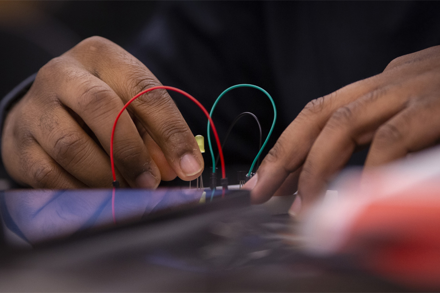 A pair of hands works with a red and green wire.