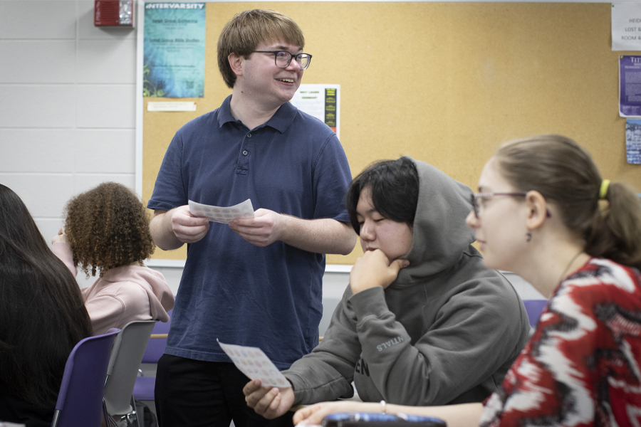 A student stands and smiles in a classroom.