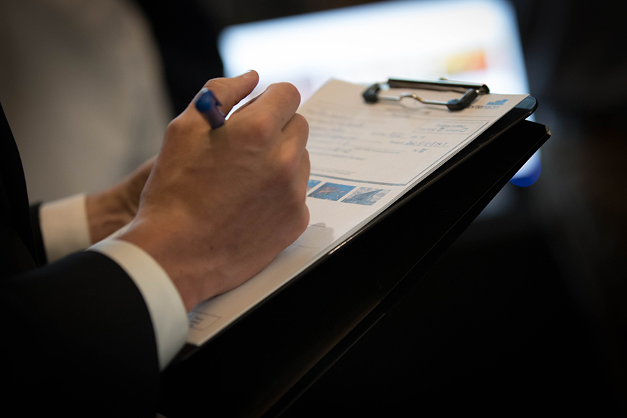 A close up photo of a hand writing on a clipboard.