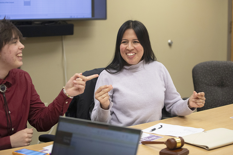 Maria Pacheco sits at a table with a smile on her face.