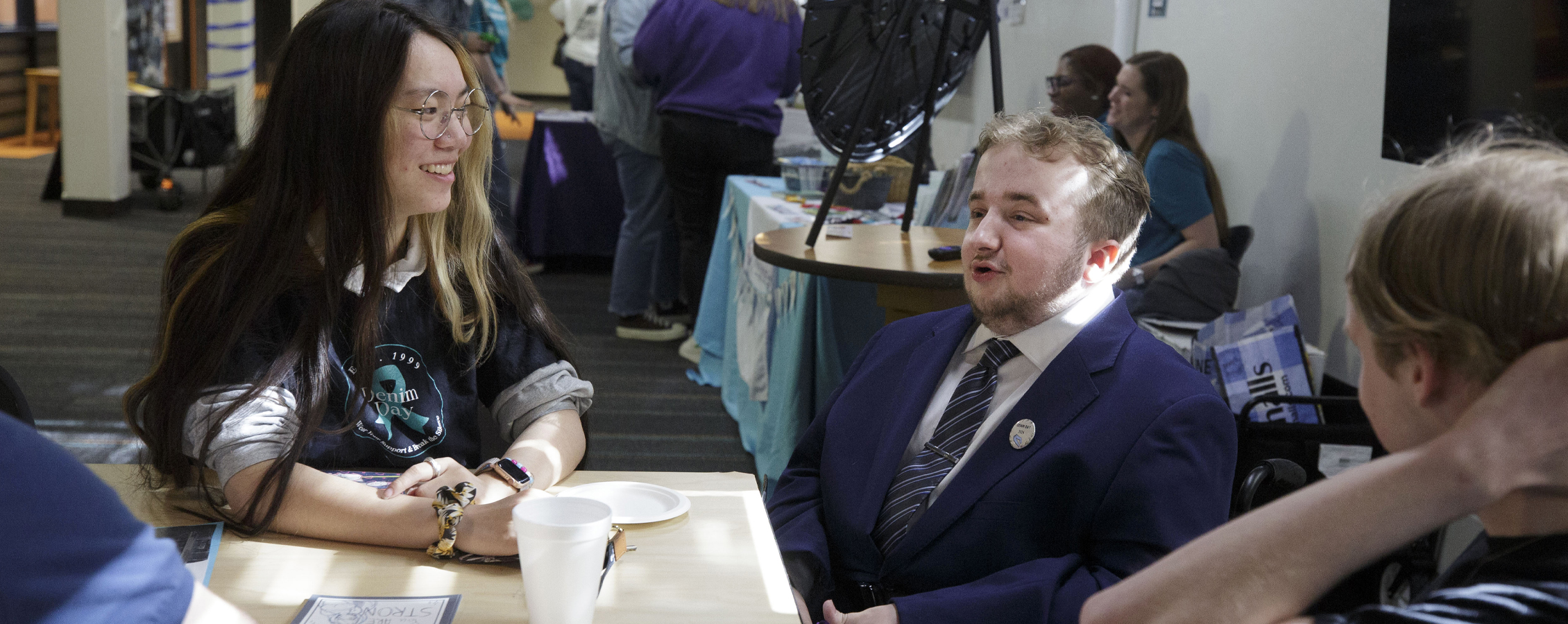 Three students chat together at a tabling event in Fricker Hall.