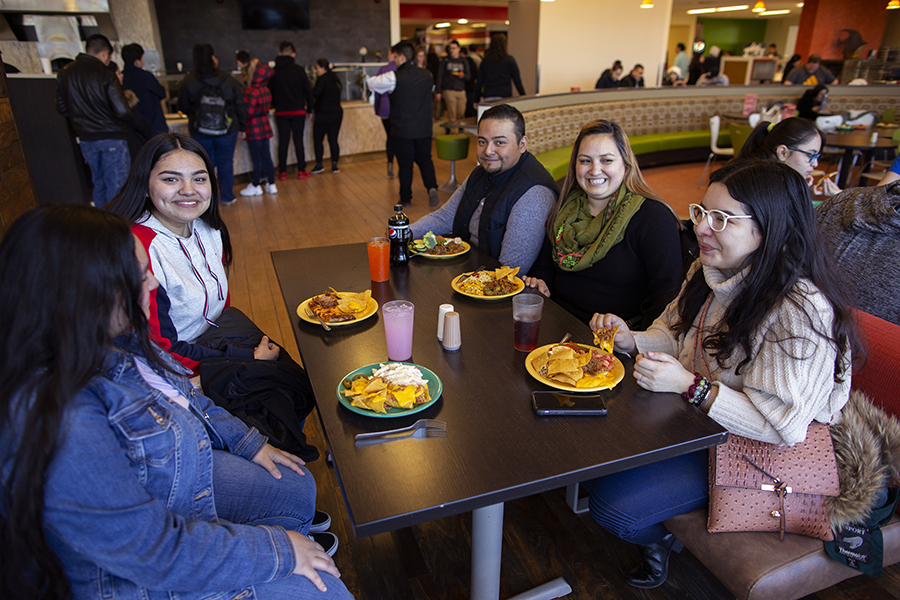 Students sit with plates of food in a dining hall.