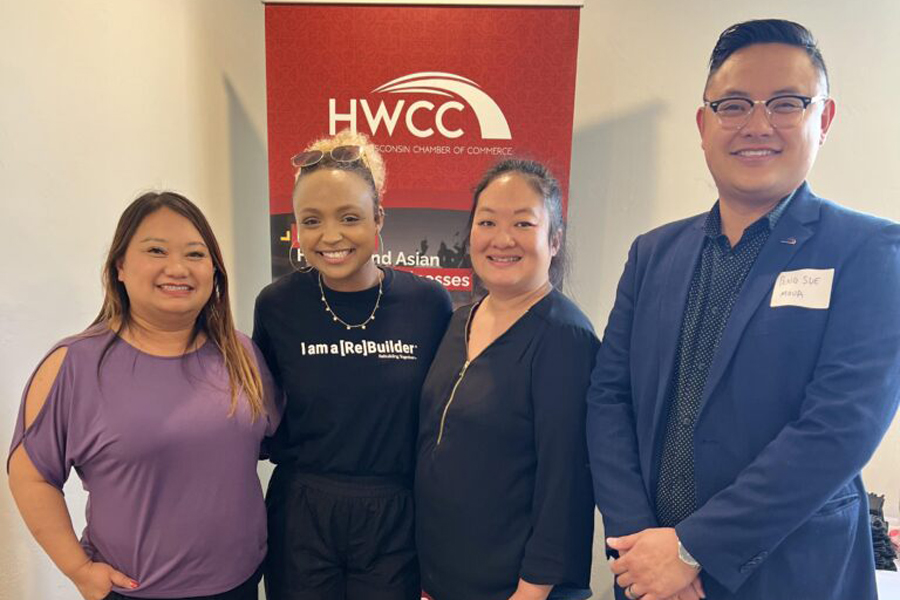 Maysee Yang Herr stands with a small group of people, smiling at the camera.